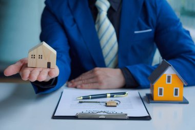 Bir emlakçı anlaşmayı imzalamak için örnek bir ev sigortası öneriyor. Satış sözleşmesinin belgeleriyle ya da kira sözleşmesiyle
