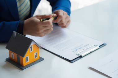 Bir emlakçı anlaşmayı imzalamak için örnek bir ev sigortası öneriyor. Satış sözleşmesinin belgeleriyle ya da kira sözleşmesiyle