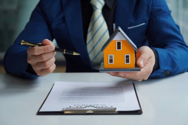 Bir emlakçı anlaşmayı imzalamak için örnek bir ev sigortası öneriyor. Satış sözleşmesinin belgeleriyle ya da kira sözleşmesiyle