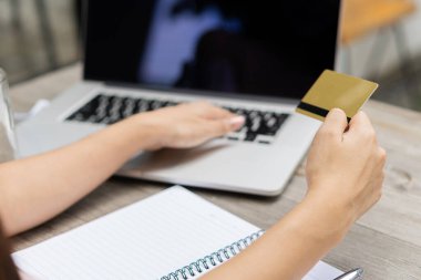 Kredi kartı tutan ve bilgisayarını evde kullanan iş adamı ya da girişimci online alışveriş e-ticaret bankacılığı yapan kadın kredi kartı kullanarak ev konseptinde para harcıyor.