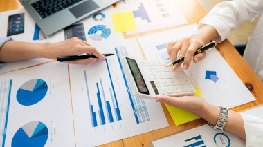 Ofiste iş görüşmesi yapan gençlerin, hesap makineli grafikler ve dizüstü bilgisayarlarla mali hesaplama verilerini analiz etmek için yaptıkları toplantıda sohbet görüntüleri..