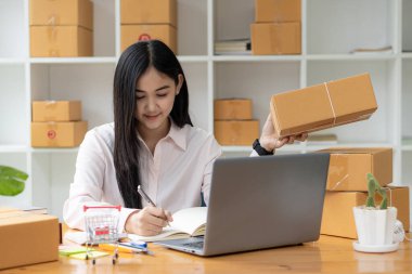 Küçük işletme girişimcisi, KOBİ ya da evde kutular ve dizüstü bilgisayarlarla, çevrimiçi satış fikirleri, e-ticaret, nakliyat, paketleme, çevrimiçi pazarlama ve nakliyat ile çalışan Asyalı serbest çalışan bir kadın kurmak.