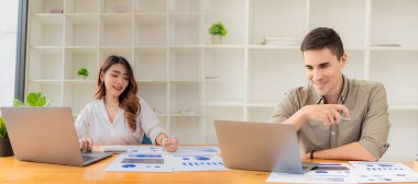 İki genç iş ortağının bir ofis toplantısında çalışan başarılı finansal grafikleri incelerken laptop ve touchpad kullanırken fotoğrafı.
