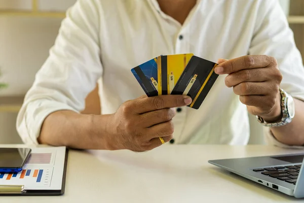 Businessman holding three credit cards the size of sitting in the office, internet banking concept.