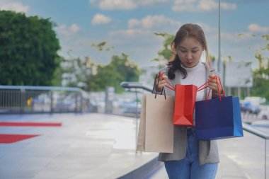 Bir butiğin önünde elinde bir alışveriş çantası olan güzel bir kız. Satış sezonunda alışveriş yaparken alışveriş yapmaktan hoşlanan zarif bir genç kadının portresi.