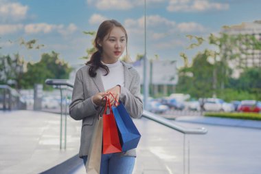 Bir butiğin önünde elinde bir alışveriş çantası olan güzel bir kız. Satış sezonunda alışveriş yaparken alışveriş yapmaktan hoşlanan zarif bir genç kadının portresi.