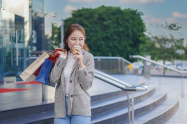 Bir butiğin önünde elinde bir alışveriş çantası olan güzel bir kız. Satış sezonunda alışveriş yaparken alışveriş yapmaktan hoşlanan zarif bir genç kadının portresi.