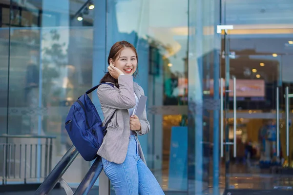 在购物中心前拿着平板电脑和手提包的女学生笑得很可爱 — 图库照片