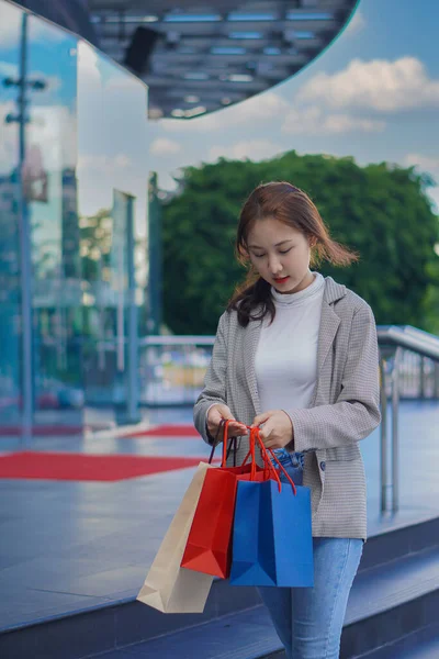 ショッピングバッグを持ったブティックの前に立つ美少女販売シーズンの百貨店で買い物をしながら買い物を楽しむ優雅な若い女性の肖像コピースペース — ストック写真