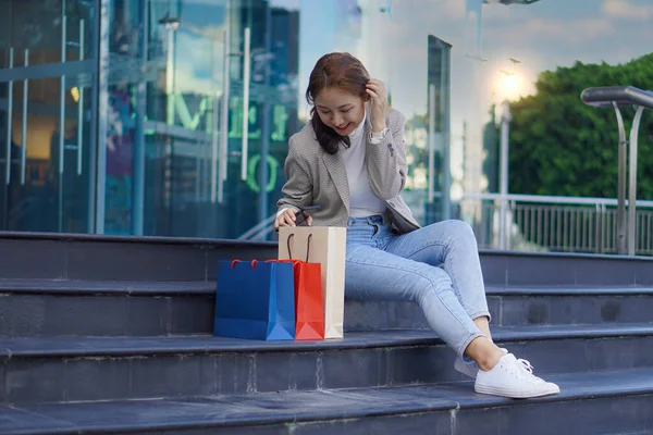 一个漂亮的女孩站在一家精品店前 手里拿着一个购物袋 描绘了一个优雅的年轻女子在百货商店购物时的形象 — 图库照片