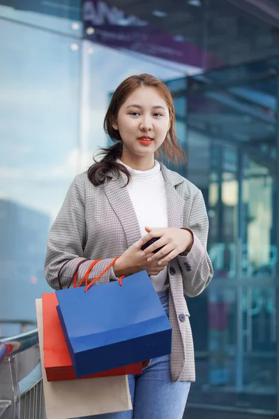一个漂亮的女孩站在一家精品店前 手里拿着一个购物袋 描绘了一个优雅的年轻女子在百货商店购物时的形象 — 图库照片