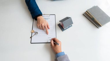 Real estate agents offer home or homeownership insurance to their clients. at the modern wooden table Signing of sales and lease agreements Broker/Seller/Dealer Concept