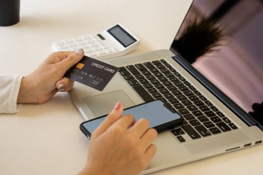 Online shopping concept paying via credit card with laptop computer and smartphone.