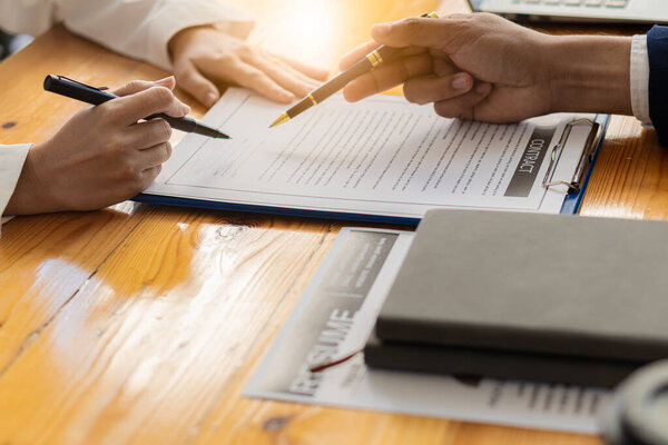 Businessmen hold resumes and talk to job applicants for job interviews about careers and CVs in the company. recruiting woman submitting a job application at the desk in the office recruiting concept
