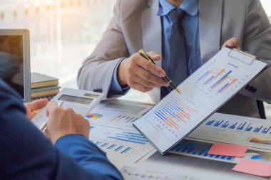 Businessman Discussing Successful Teamwork Teamwork Charts and Graphs Businessman working in the office discussing papers and ideas in meeting with laptop and calculator to calculate and analyze.