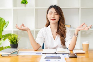 Ofis işi sırasında konsantrasyonda oturan Asyalı kadın muhasebeci ve masadaki mali tablo.