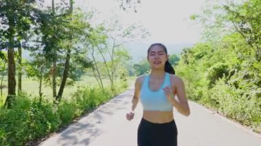 Akşam günbatımında parkta sağlık için koşan güzel Asyalı kadın. Sağlığı için açık hava.