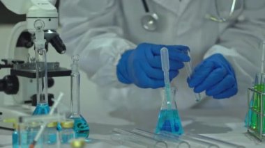 Maskeli erkek bilim adamı, ilaç biyoteknoloji gelişimi için gelişmiş bilimsel laboratuvarı analiz etmek için mikro pipet kullanıyor. Tıbbi araştırmalar yapan bilim adamları tüp bebek deneyleri yapıyor..