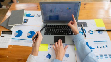 Modern ve kavramsal ofis tasarımını planlamak için takım toplantısı. Piyasa durumunu tartışmak için finansal grafik belgeleri ve hesap makinesi bilgisayarı üzerinde çalışan iş adamlarının elleri, üst görünüm.