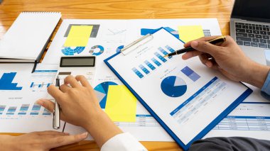 Finans ve muhasebe sektöründe çalışan iş adamları mali bütçeyi analiz ediyor ve çalışmak için hesap makinesi kullanmayı planlıyorlar. Gelir giderlerini hesaplıyorlar. ve gayrimenkul yatırım verilerini analiz etmek