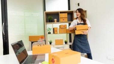 Küçük işletme, KOBİ, Evde çalışan bağımsız girişimci Asyalı kadın, karton kutular, akıllı telefonlar, dizüstü bilgisayarlar, çevrimiçi, pazarlama, ambalaj, ulaşım, KOBİ, e-ticaret kavramı.