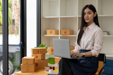 Küçük işletme, KOBİ, Evde çalışan bağımsız girişimci Asyalı kadın, karton kutular, akıllı telefonlar, dizüstü bilgisayarlar, çevrimiçi, pazarlama, ambalaj, ulaşım, KOBİ, e-ticaret kavramı.
