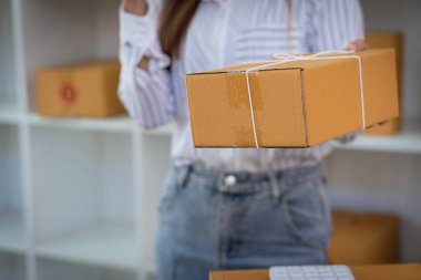 Küçük bir işletme kurun KOBİ girişimcisi veya bağımsız genç Asyalı kadın kutu çevrimiçi pazarlama ve teslimat, KOBİ ev işi kavramı olan bir dizüstü bilgisayar kullanarak.