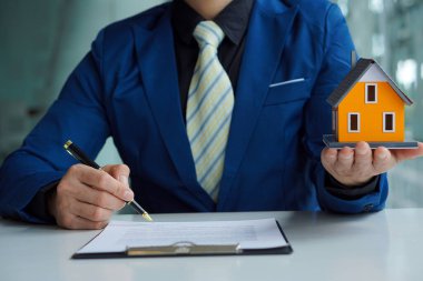 Emlakçıların elinde ev tasarımları ve ev satın alma sözleşmeleri var. Faiz oranları hesaplanan sigorta veya ofisteki emlak kredileri