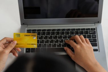 Genç kadınlar kredi kartı tutuyor ve bilgisayarlarını E-ticaret internet bankacılığı için kullanıyor. Çevrimiçi ürün alımlarına para harcıyor, kredi kartıyla online alışveriş yapıyor..