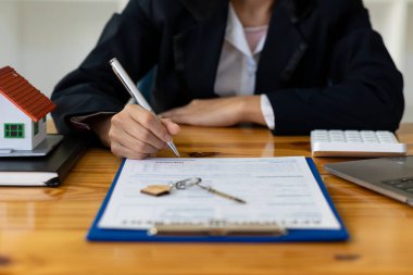İnsanlar gayrimenkul ve ev alımlarına yatırım yapmak için faiz, vergi ve kâr hesaplıyorlar. Ev düzeni olan emlakçılar müşterilerle ev sigortası hakkında konuşuyorlar..