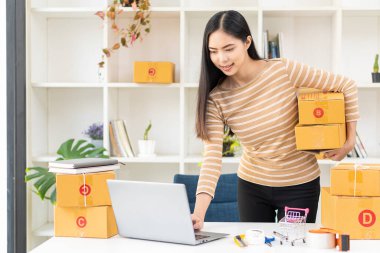 Ev bilgisayarında çalışan Asyalı bir kadın müşterilerden emir almak için internetten bilgisayar başında çalışıyor..