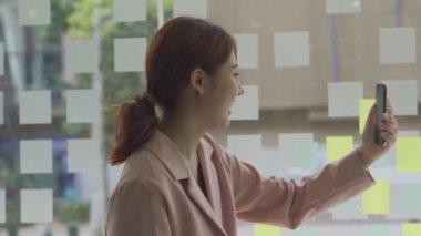 Mutlu Asyalı kadın videosu akıllı telefon kullanarak arkadaşına el sallıyor. İnternet iletişim kavramı