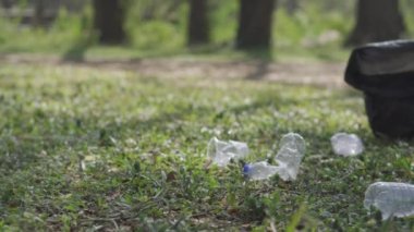 Sosyal parkta orman güvenli ekoloji konseptini temizleyen gönüllüler. Yakın plan. Gönüllü eller, park çimenlerinden plastik şişeleri topluyor. Plastiği durdur. Sivil yükümlülük. çevre kavramı