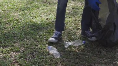 Sosyal parkta orman güvenli ekoloji konseptini temizleyen gönüllüler. Yakın plan. Gönüllü eller, park çimenlerinden plastik şişeleri topluyor. Plastiği durdur. Sivil yükümlülük. çevre kavramı