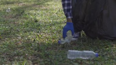 Sosyal parkta orman güvenli ekoloji konseptini temizleyen gönüllüler. Yakın plan. Gönüllü eller, park çimenlerinden plastik şişeleri topluyor. Plastiği durdur. Sivil yükümlülük. çevre kavramı