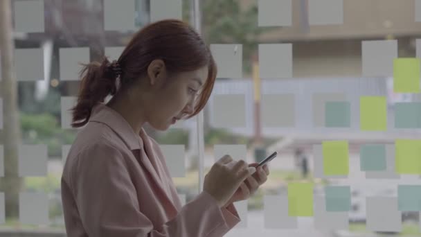 アジアの女性は インターネット上で電子メールメッセージを送信することにより 彼女の友人に話すためにスマートフォンを使用しています — ストック動画