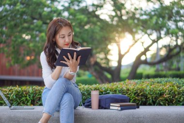 Genç Asyalı kampüs öğrencileri kaplan derisi eğitimi ve açık hava üniversite kavramları tutuyorlar.