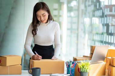 Küçük bir İşletme, KOBİ sahipleri ve Kadın Girişimciler, kutu hazırlamak için dizüstü bilgisayarla fatura kutuları üzerinde çalışır ve çevrimiçi siparişleri kontrol ederler. Müşterilere satıyorum. Çevrimiçi KOBİ iş fikri.