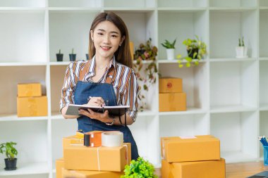 Genç Asyalı Kadınlar Küçük İş Başarı KOBİ Girişimcisi .freelance Home-Home-Woman sipariş almak ve paketleri çevrimiçi teslim etmek için bilgisayarla çalışıyor. KOBİ dağıtım kavramı ve ambalaj
