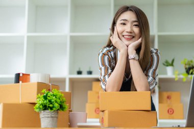 Genç Asyalı Kadınlar Küçük İş Başarı KOBİ Girişimcisi .freelance Home-Home-Woman sipariş almak ve paketleri çevrimiçi teslim etmek için bilgisayarla çalışıyor. KOBİ dağıtım kavramı ve ambalaj