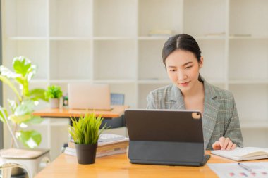 Asyalı kız online alışveriş tableti kullanarak online alışveriş yapıyor. Kredi kartı, akıllı telefon, akıllı ödeme, para transferi teknolojisi kullanıyor.