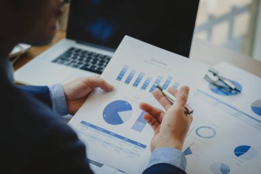 Finans grafiği tutan bir işadamı, mali istatistik, hisse senedi resimleri, tartışma ve veri analizi, grafikler ve grafikler içeren bir belge. muhasebe kavramı