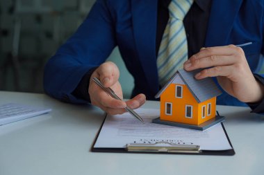 Satış temsilcisi. Ev tutmak, müşterilere kontrat imzalamayı teklif etmek. Resmi belgeleri imzala. Müşteri ortakları gayrimenkul alıp satıyor. Satış temsilcisi bir ev satın almak için sözleşme teklif ediyor..