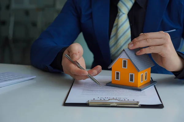 Sales representative. Holding a house, offering customers to sign a contract. Sign official documents. Customer partners buy or sell real estate. The sales representative offers a contract to purchase a house.