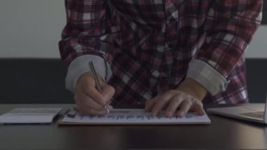 Finans ve ekonomi aylık gider hesapları ve borç ödenmesi kavramı. Gençler hesap makinesi kullanıyor. Yurtiçi gelirini ve vergi belgelerini evde say.