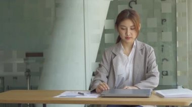 Finans muhasebesinde çalışan Asyalı bir kadın dizüstü bilgisayarla iş konsepti tablosunun hesaplama analizinde doküman çiziyor..