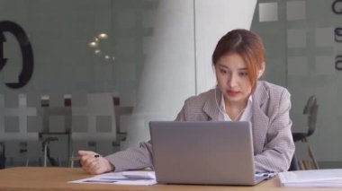 Finans muhasebesinde çalışan Asyalı bir kadın dizüstü bilgisayarla iş konsepti tablosunun hesaplama analizinde doküman çiziyor..