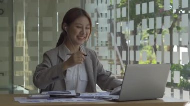 Finans muhasebesinde çalışan Asyalı bir kadın dizüstü bilgisayarla iş konsepti tablosunun hesaplama analizinde doküman çiziyor..