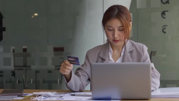 ホワイトルームで携帯電話を使用してクレジットカードを保持しているアジアの女性ビジネスコンセプトテーブル上の計算分析でノートパソコンやグラフ文書でオフィスでモバイルオンライン決済や予約 — ストック動画