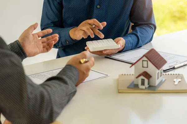 Real estate professionals offer their clients contracts to discuss home purchases, insurance or real estate loans. Home sales agents sit at the office with new home buyers in the office.